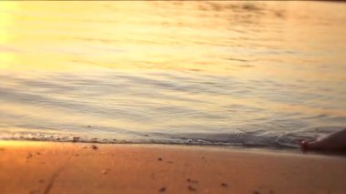 Sahilde yalın ayak yürüyen bir kadın.