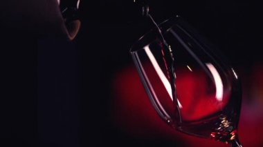 kırmızı şarap bardağa dökülüyor.