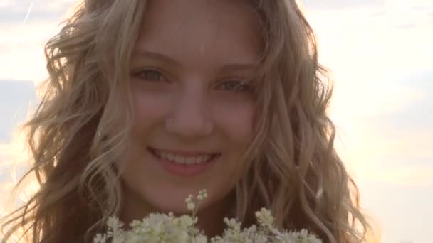 Chica oliendo flores silvestres — Vídeo de stock