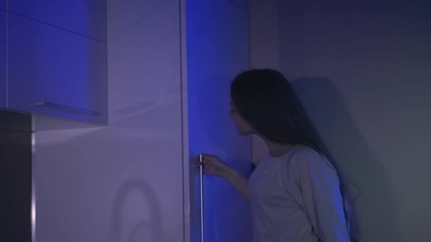 Девушка получает торт из холодильника ночью — стоковое видео