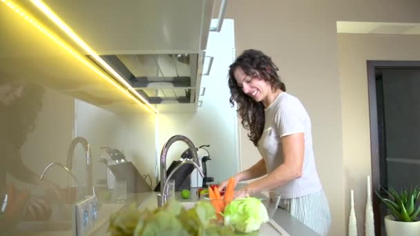 Jovem mulher em legumes de lavagem de cozinha — Vídeo de Stock