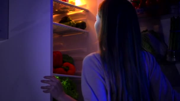 Дівчина отримує торт з холодильника вночі — стокове відео
