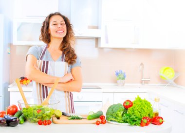 Kadın mutfakta yemek pişiriyor.