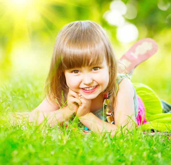 Kleines Mädchen liegt auf grünem Gras — Stockfoto