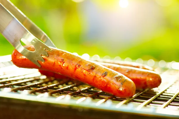 Salsicce alla griglia sulla griglia fiammeggiante . — Foto Stock