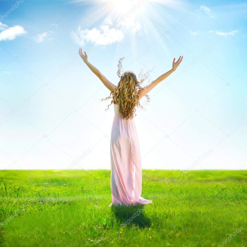 woman raising hands in sunlight rays