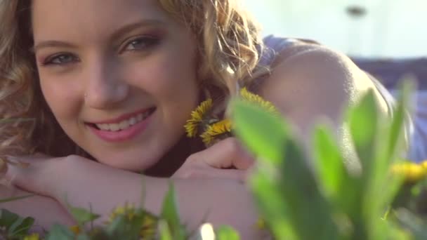 Chica acostada en flores de diente de león — Vídeos de Stock