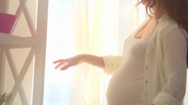 Hamile bir kadın karnını okşuyor.