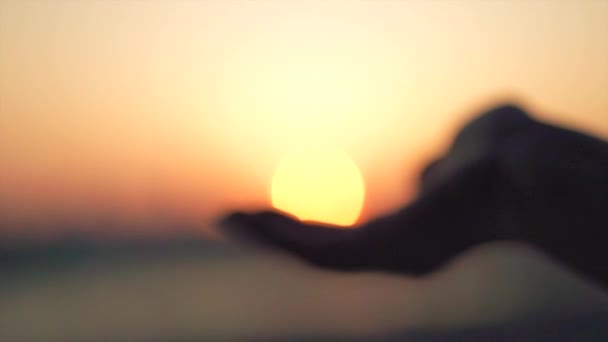 Main prenant un soleil contre la mer — Video