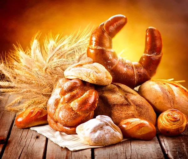 Verschiedene Brotsorten und Weizenähren — Stockfoto