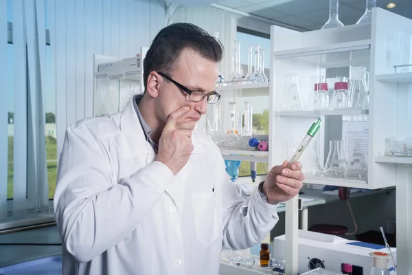 Trabajador de laboratorio en gafas observando tubo de ensayo con molde en el laboratorio —  Fotos de Stock