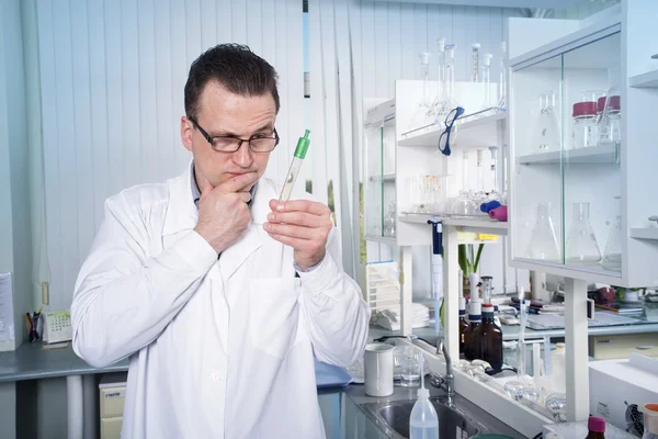 Trabalhador de laboratório em óculos observando tubo de ensaio com molde no laboratório — Fotografia de Stock