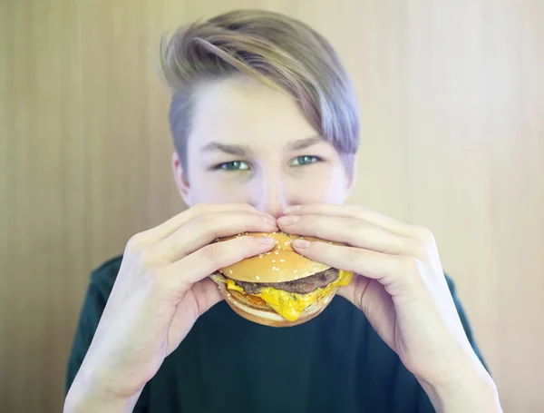 Boy eats hamburger — Stockfoto