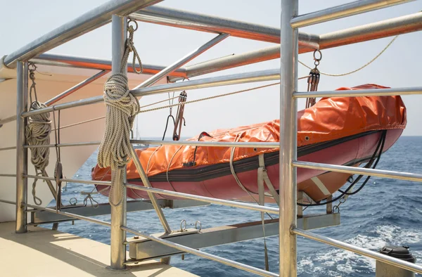 Помаранчевий рятувальний човен, що висить на кораблі в морі — стокове фото