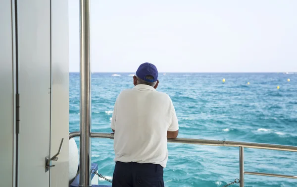 Mann auf einem Bootsdeck, der allein aufs Meer blickt — Stockfoto
