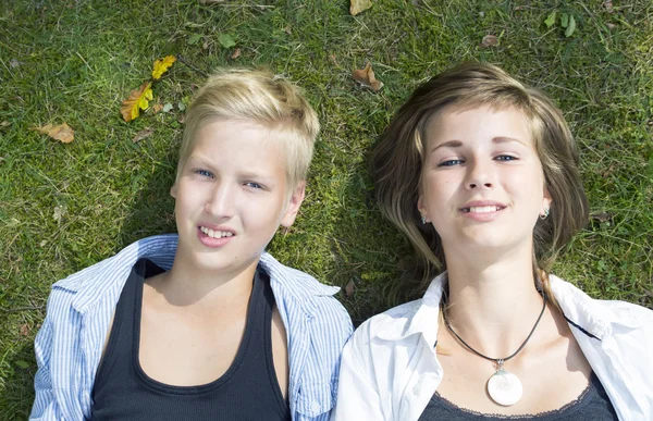 Lächelnde Jungen und Mädchen (Geschwister) liegen auf dem grünen Gras in der Natur — Stockfoto