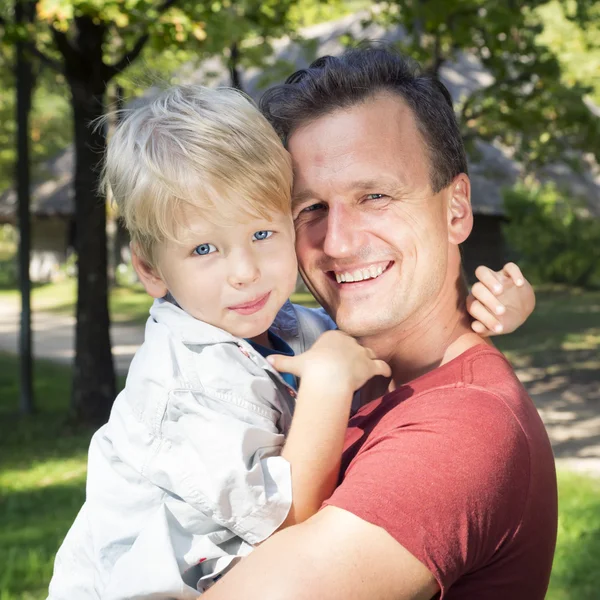 Lycklig pappa håller sin son, lilla roliga unge pojke arm solig dag — Stockfoto