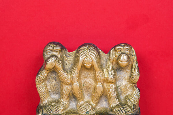 Brass statue of three monkeys isolated on wooden surface.