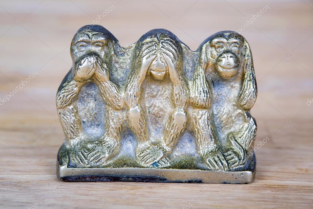 Brass statue of three monkeys isolated on wooden surface. — Stock Photo
