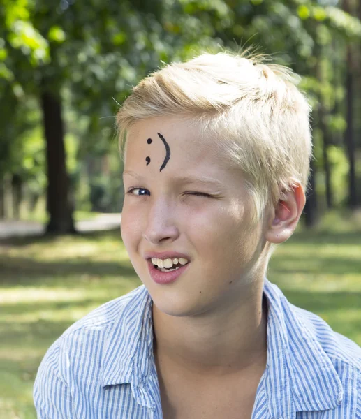 Il ragazzo ammiccante siede sull'erba verde nella foresta. Concetto di felice tu — Foto Stock