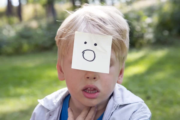 Överraskande boy sitter på grönt gräs i skogen. — Stockfoto