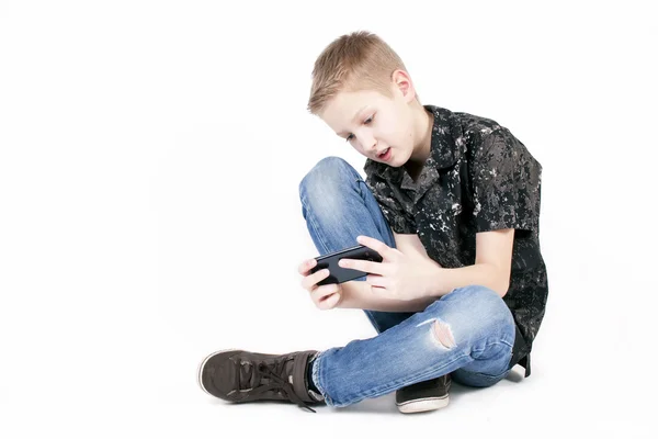 Adolescente menino procurando algo em um telefone inteligente isolado . — Fotografia de Stock