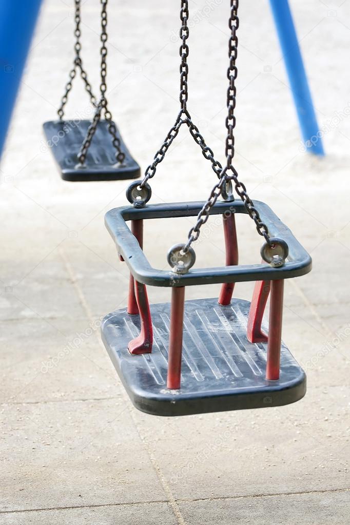 Empty swing on children playground in city.