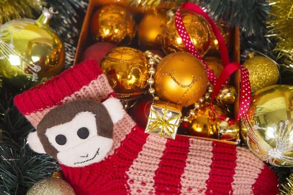 Christmas background with colored balls and monkey on red sock. — Stock Photo, Image