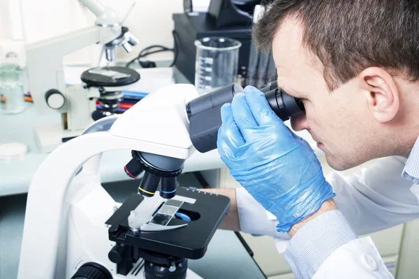 Cientista olhando através do microscópio em laboratório — Fotografia de Stock