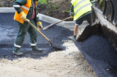 asfalt yol yapımı, kürek ile yaparken işçi