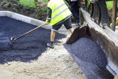 asfalt finişer makine yol yapımı sırasında işletim ve onarma işçi çalışıyor