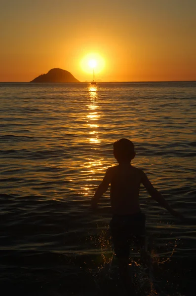 Criança brincando ao pôr do sol na praia de Itaipu — Fotografia de Stock