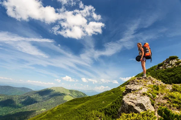 Young woman with backpack standing on cliff — Stock Photo, Image