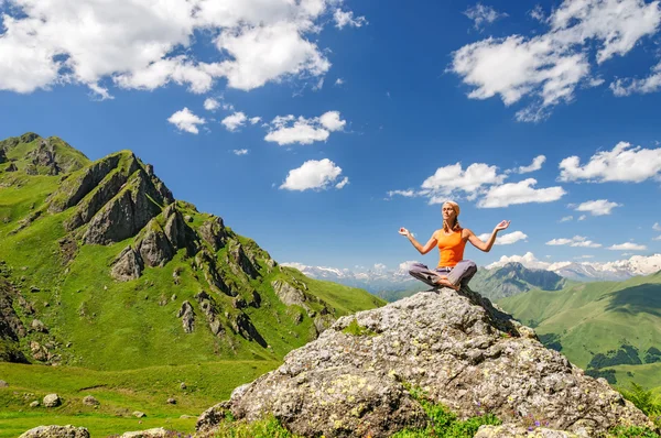 Mujer joven sentada en yoga posan en las montañas Fotos De Stock