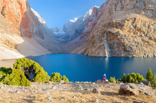 Yalnız bir adam güzel dağ Gölü kıyısında oturuyor — Stok fotoğraf