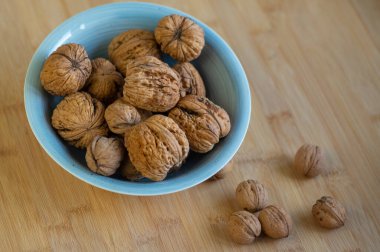 Sert kabuklarda cevizler, mavi kasede kurumuş meyveler, pişirmeye ve pişirmeye hazır sağlıklı besinler.