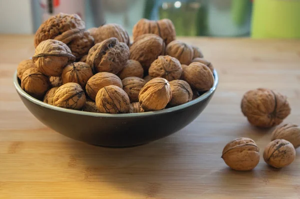 Walnuts on table in hard shells, group of dry ripened fruits in black and white bowl, harvested healthy food ingredients ready for baking and cooking