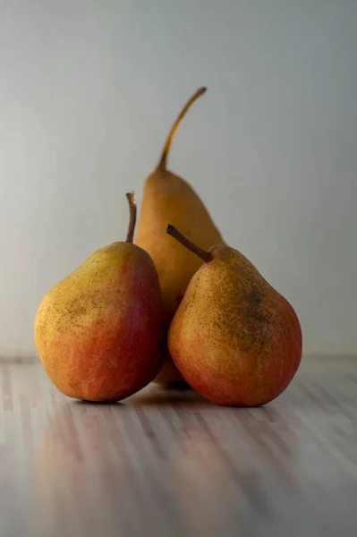 Three pears edible fruits, tasty ripened red yellow fruit still life on wooden background