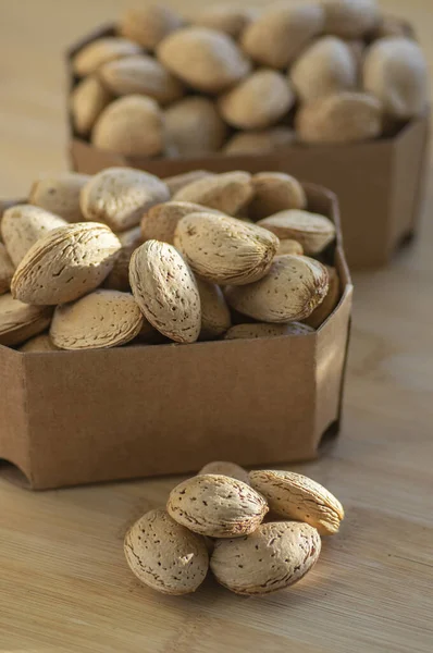 Almonds on table in hard shells, group of dry ripened fruits in brown cardboard boxes, harvested healthy food ingredients ready for baking and cooking