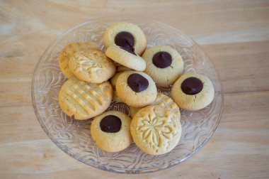 Koyu çikolatayla doldurulmuş açık kahverengi bej fıstıklı kurabiyeler. Tabakta, lezzetli Noel tatlıları servis ediliyor.