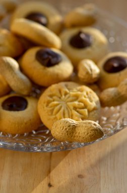 Koyu çikolatayla doldurulmuş açık kahverengi bej fıstıklı kurabiyeler. Tabakta, lezzetli Noel tatlıları servis ediliyor.