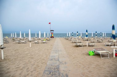 Kapalı şemsiyeli ve güneşli plaj, güneşli şezlonglar ve şemsiyeli, sabahın erken saatlerinde Sottomarina, İtalya, Avrupa 'da