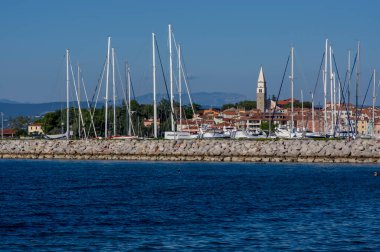 Izola, SLOVENIA - 12 Eylül 2019: Izola 'nın eski balıkçı kasabası tarihi merkezi, kilise kulesi ve ön planda tekneleri olan marina manzarası