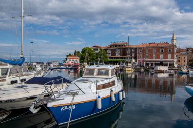 Izola, SLOVENIA - 8 Eylül 2019: Izola 'nın eski balıkçı kasabası tarihi merkezi, kilise kulesi ve ön planda tekneleri olan marina manzarası