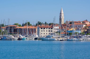 Izola, SLOVENIA - 12 Eylül 2019: Izola 'nın eski balıkçı kasabası tarihi merkezi, kilise kulesi ve ön planda tekneleri olan marina manzarası