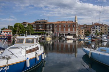 Izola, SLOVENIA - 8 Eylül 2019: Izola 'nın eski balıkçı kasabası tarihi merkezi, kilise kulesi ve ön planda tekneleri olan marina manzarası
