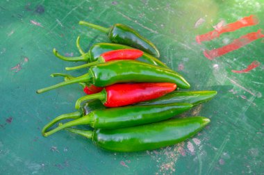 Capsicum annuum Jalapeno acı biber, ahşap renkli masa arkasında yeşil ve kırmızı meyveler, olgunlaşmamış ve olgunlaşmamış.