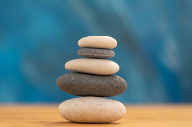 Mavi arka planda taş cairn, beş taş kule, basit denge taşları, sadelik ahenk ve denge