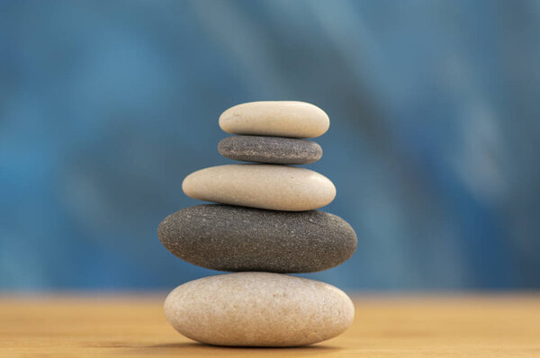 Stone cairn on blue backgrounds, five stone tower, simple poise stones, simplicity harmony and balance