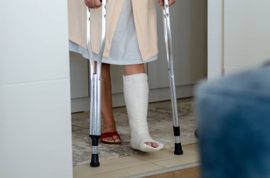 Kırık bacaklı orta yaşlı kadın. Ayakta duruyor ve eve yürümeye çalışıyor..